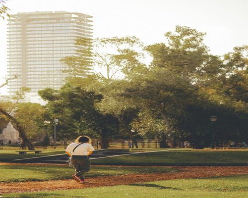 Person walking leisurely in a green urban park in San Isidro at sunset